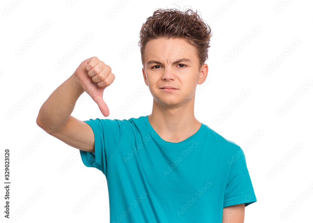 Portrait of teen boy giving thumb down gesture looking with negative expression and disapproval. Handsome caucasian young teenager doing bad signal, isolated on white background. Portrait of teen boy giving thumb down gesture looking with negative expression and disapproval. Handsome caucasian young teenager doing bad signal, isolated on white background.