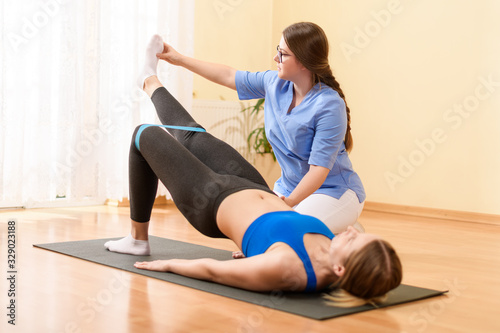 Female patient exercising with her physiotherapist using resistance band. Physical therapy concept.