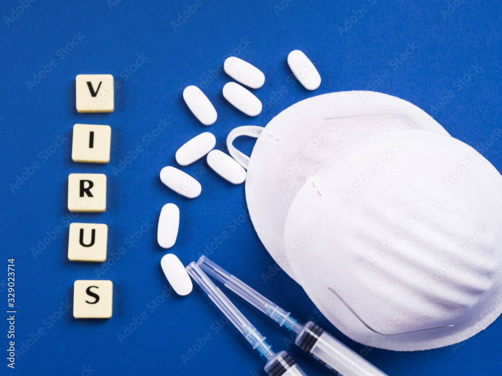 Fototapeta premium Viral disease treatment and prevention concept. Epidemic danger prevention. Treatment concept with masks, syringes and antibiotic pills on blue background