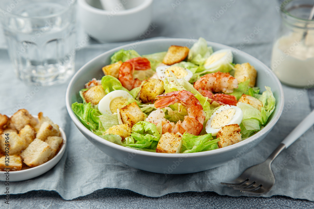 Caesar salad with prawn, roasted chicken, croutons and cheese in blue bowl Caesar salad with prawn, roasted chicken, croutons and cheese in blue bowl