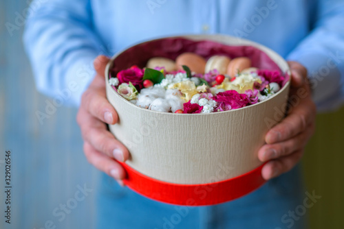 Floral shop concept . Florist man creates flower arrangement in a round box. Beautiful bouquet of mixed flowers. Handsome fresh bunch. Flowers delivery.