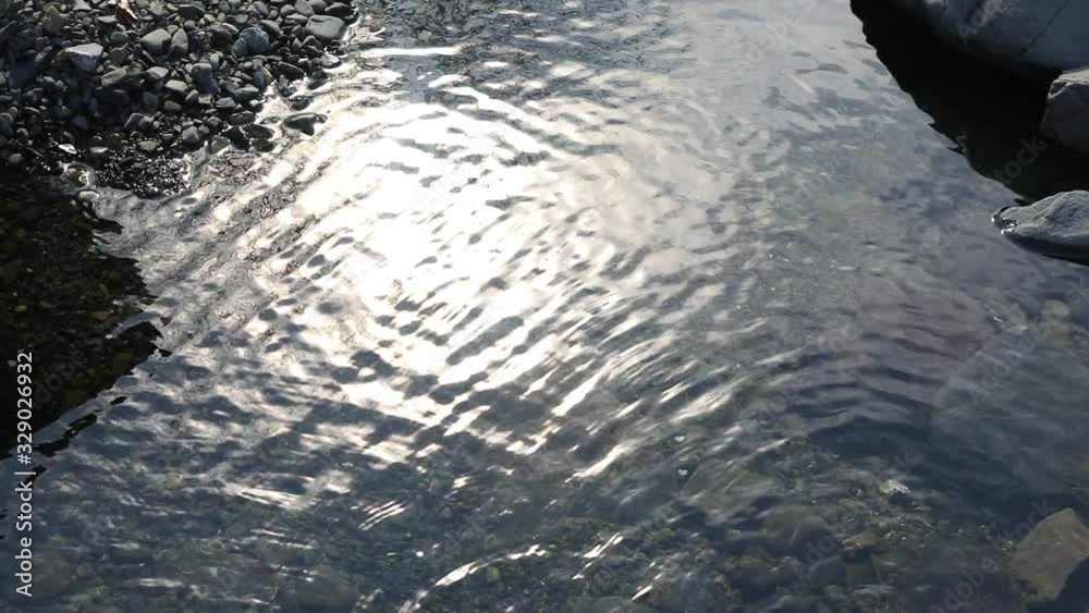 summer sunshine creates beautiful patterns on river stones under water. Nature shot summer sunshine creates beautiful patterns on river stones under water. Nature shot