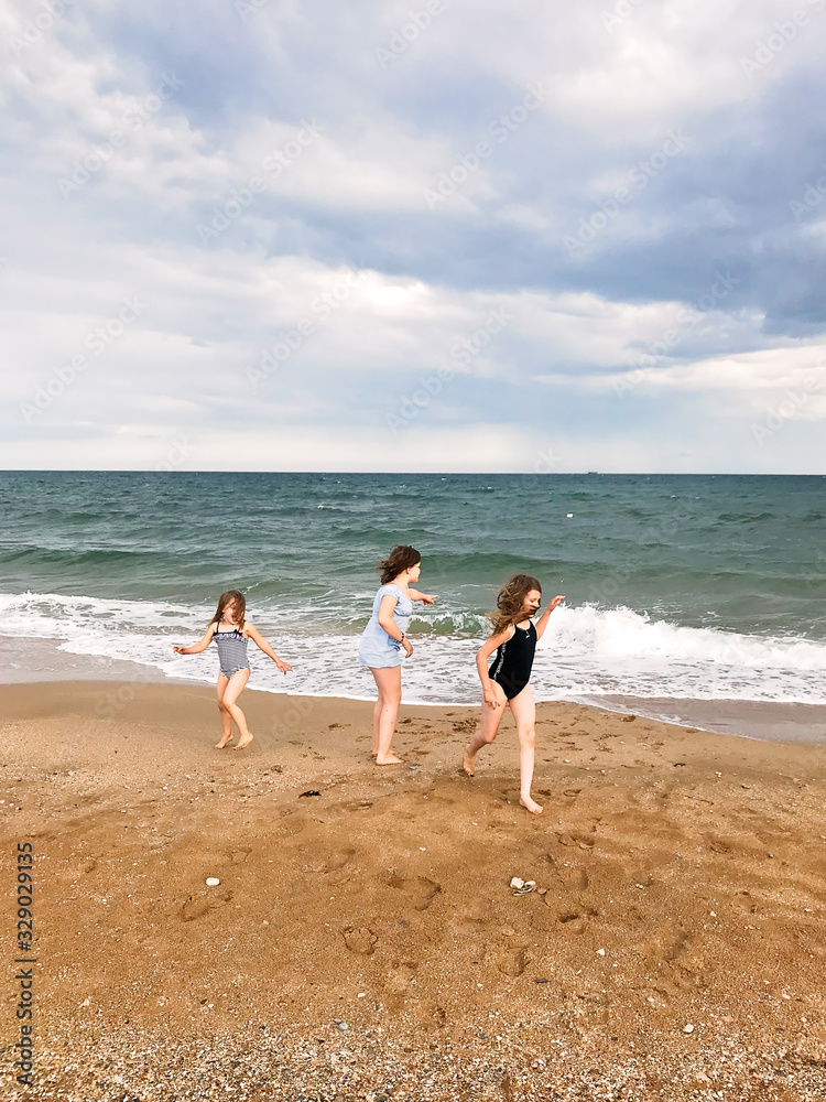 Three children on beach run and play with waves Three children on beach run and play with waves