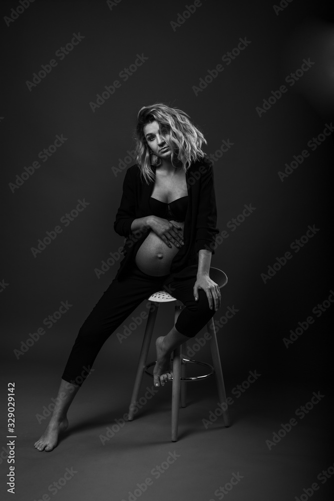 vertical portrait of a beautiful pregnant woman in the studio against a dark background