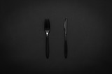 Fork and knife on dark background for minimalist flat lay black food concept.