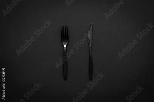 Fork and knife on dark background for minimalist flat lay black food concept. photo