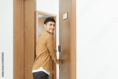 Man coming home from work and opening door of apartment