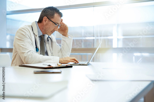 Doctor in hospital office working on laptop