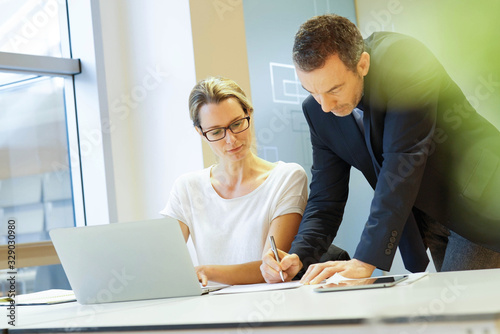 Manager signing financial document for assistant