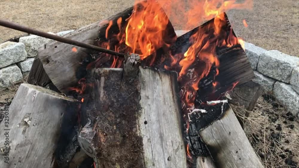 Close up shot of fire poker moving burning log in fire pit, slow motion Close up shot of fire poker moving burning log in fire pit, slow motion