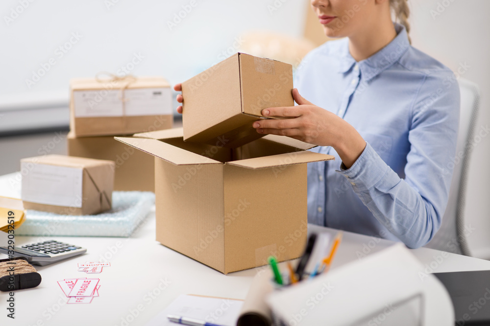delivery, mail service, people and shipment concept - close up of woman packing parcel box at post office delivery, mail service, people and shipment concept - close up of woman packing parcel box at post office