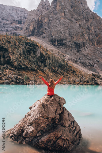 Young woman standing on a huge rock in Lake the Sorapis in italian Alps / Lago di Sorapiss