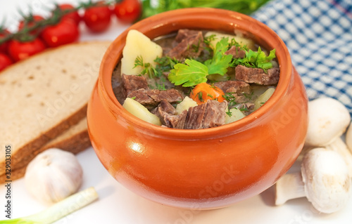 Roast in a pot with beef meat and potatoes on the table