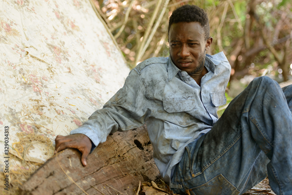 Obraz premium Sad young homeless African man sitting in the streets
