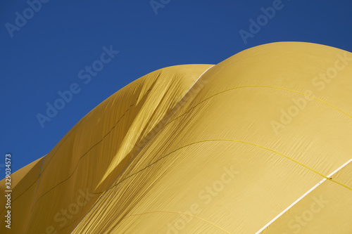 detail of yellow hot air balloon on background of sky with clouds.