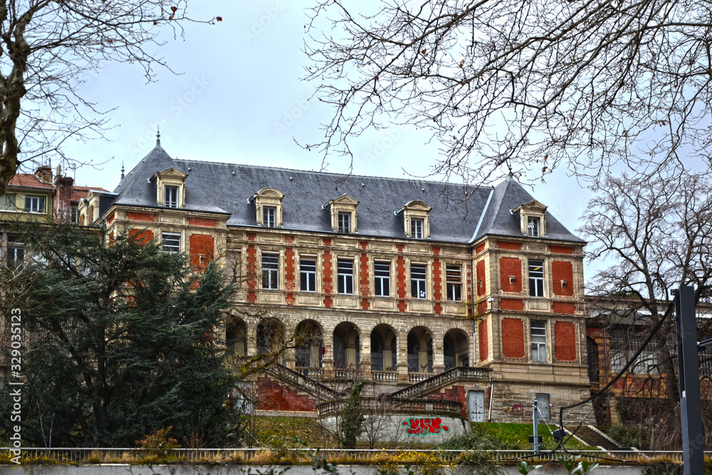 Saint-Etienne, France - January 27th 2020 : Focus on a large building made of red bricks and stones, located on one of the hills of the city. It was before the Fine arts school.