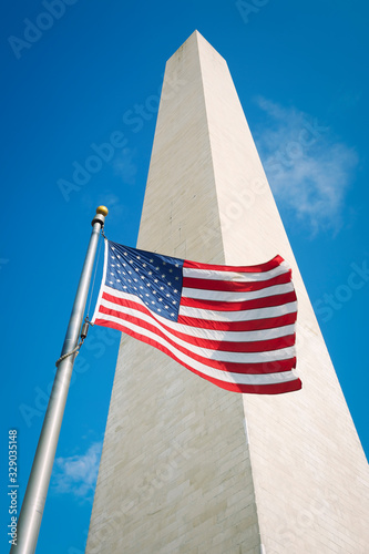 American flag flying outdoors in bright sun at the foot of the Washington Monument in Washington, DC, USA