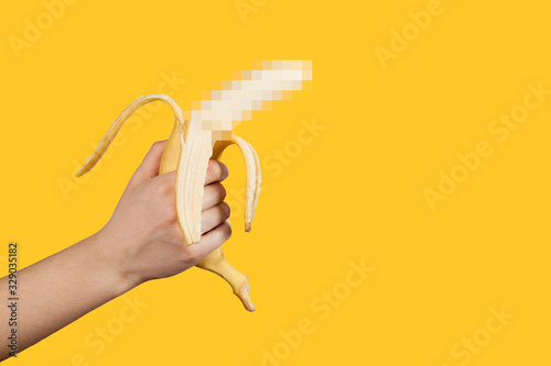 Banana as a symbol of male penis in hand on a yellow background hidden by censorship. Sexual masturbation and orgasm, impotence problem. Self-pleasure concept. photo