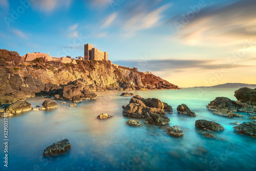 Fototapeta Naklejka Na Ścianę i Meble -  Talamone rocky beach and medieval fortress at sunset. Maremma Argentario, Tuscany, Italy