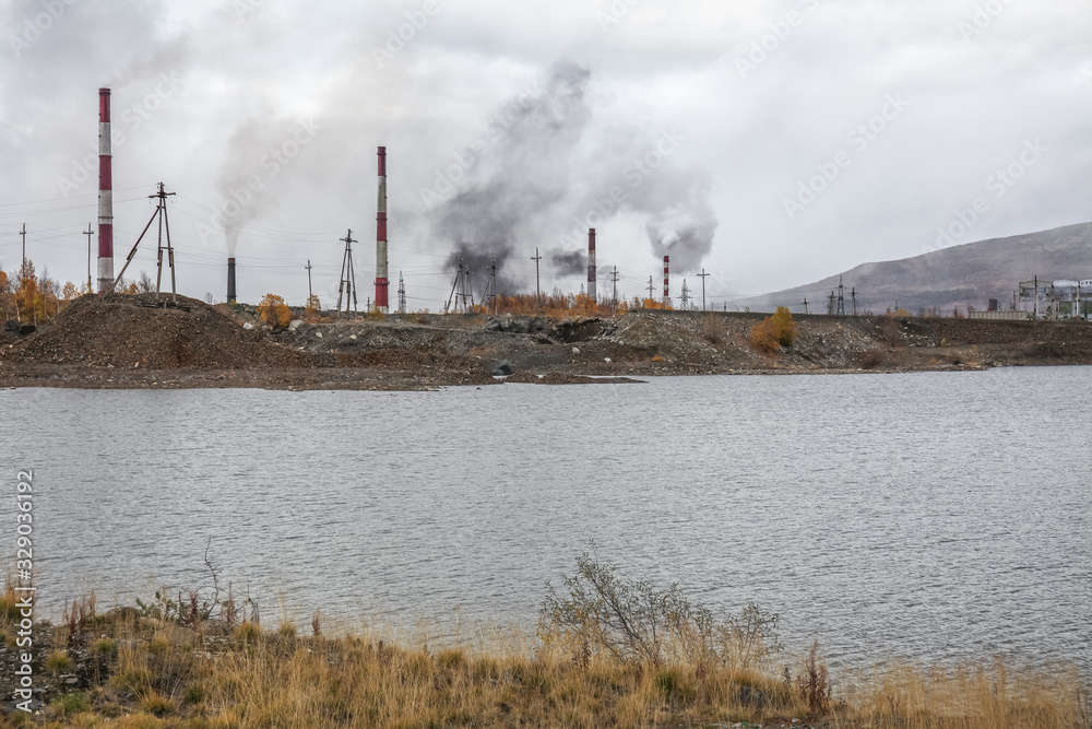 Smoke and ecology. pipes of thermal power plants against a blue sky. A stream of black smoke comes out of the right pipe Smoke and ecology. pipes of thermal power plants against a blue sky. A stream of black smoke comes out of the right pipe