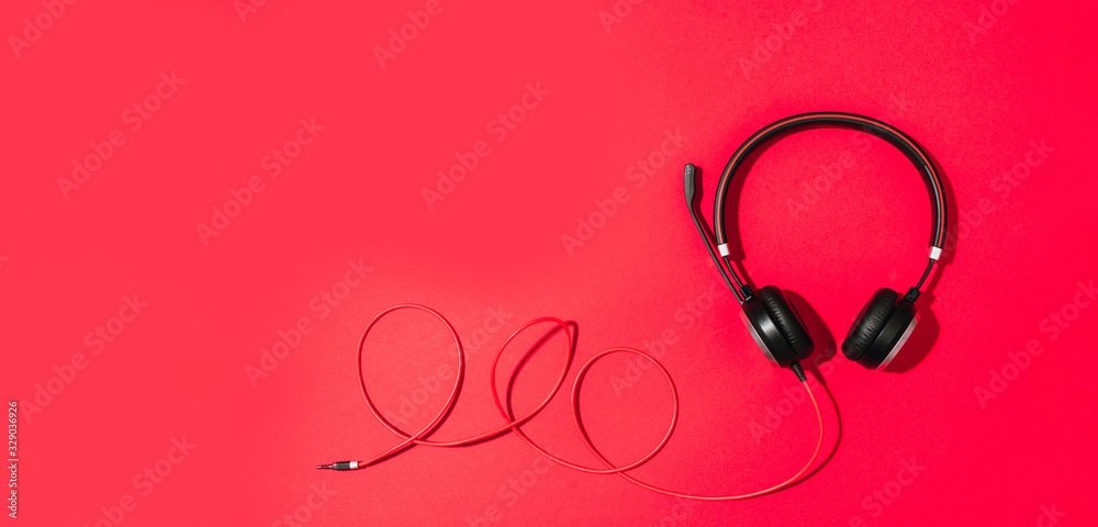 Music and sound concept. Style black headphones on red background. Top view. Copy space. Urban summer time. Banner Music and sound concept. Style black headphones on red background. Top view. Copy space. Urban summer time. Banner