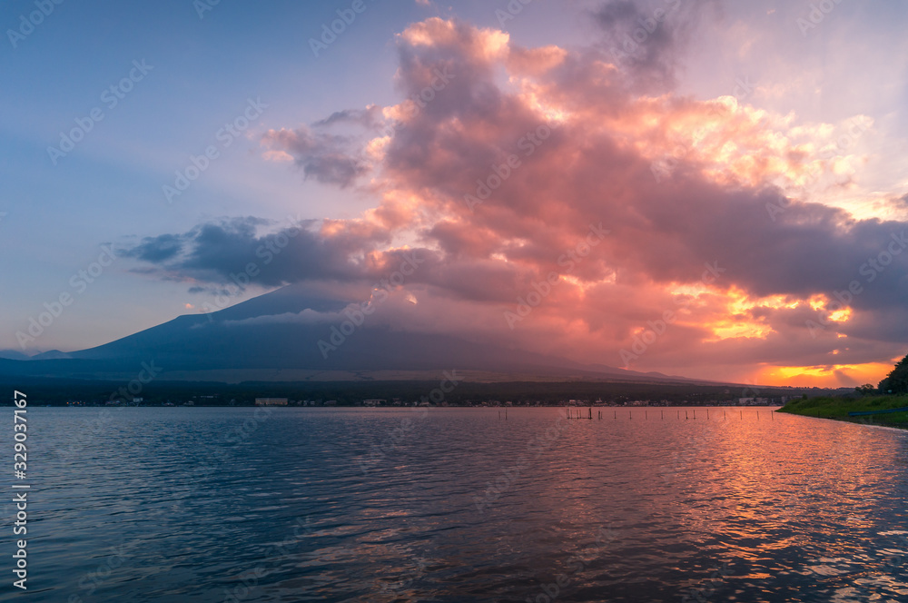 Lake landscape with mount Fuji in the clouds on the background  at sunset
