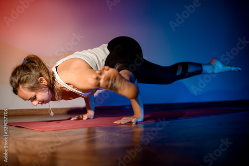 Pretty young woman working out in studio and doing yoga pose