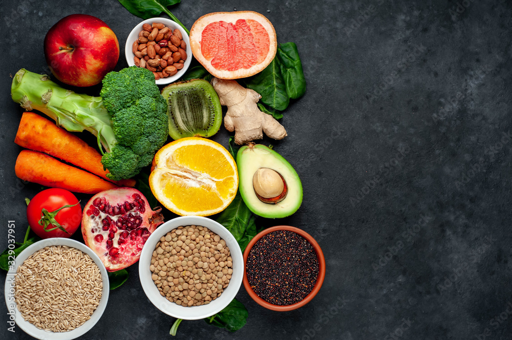Selection of healthy food:  fruits, seeds, cereals, superfoods, vegetables, leafy vegetables on a stone background. Healthy food for humans. Copy space for your text.