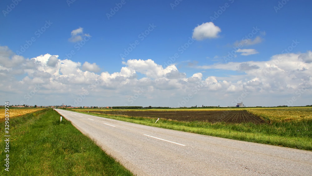 Asphalt road through the valley with agricultural fields 