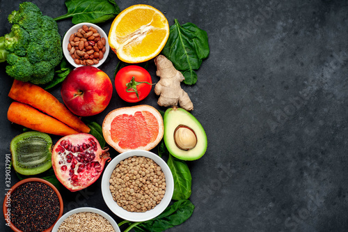Selection of healthy food   fruits  seeds  cereals  superfoods  vegetables  leafy vegetables on a stone background. Healthy food for humans. Copy space for your text.