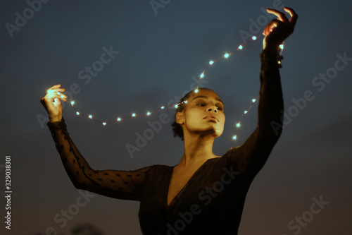 Plakat w ramie Ragazza tiene delle luci di notte in segno di libertà e relax