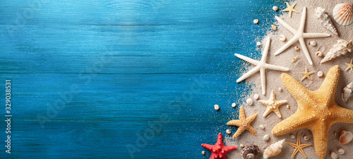 Fotografia Seashell, starfish and beach sand on blue wooden background