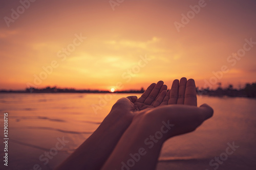 Woman open hand up on tropical sunset background.