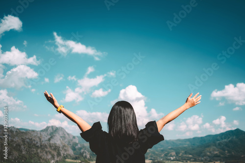 Woman raise hand up at top of mountain on blue sky and white cloud abstract background.