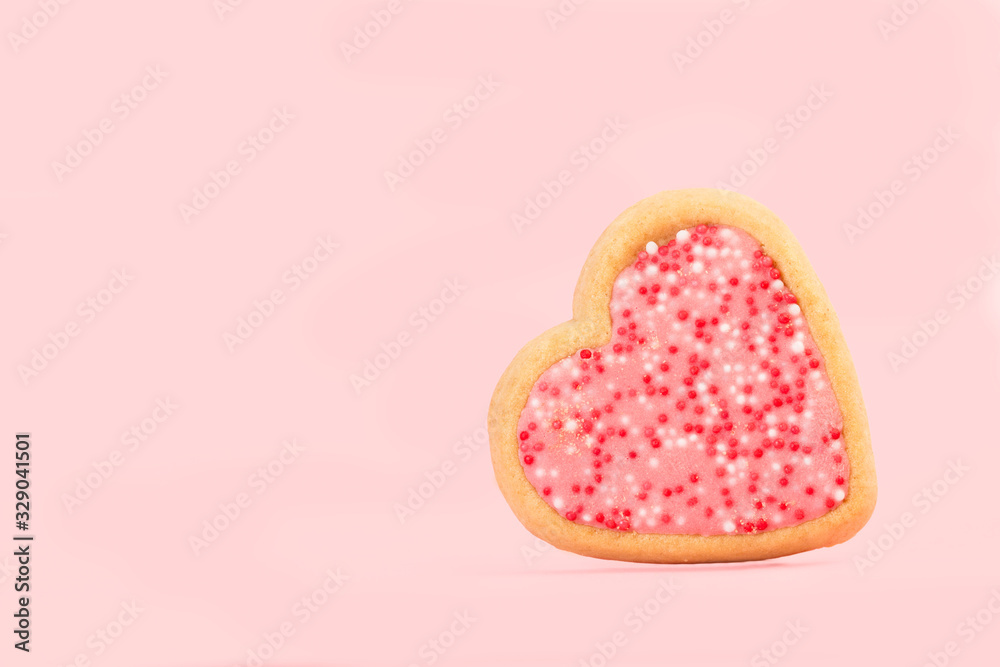 Galleta en forma d ecorazón sobre fondo liso rosa aislado. vista de frente. Copy space
