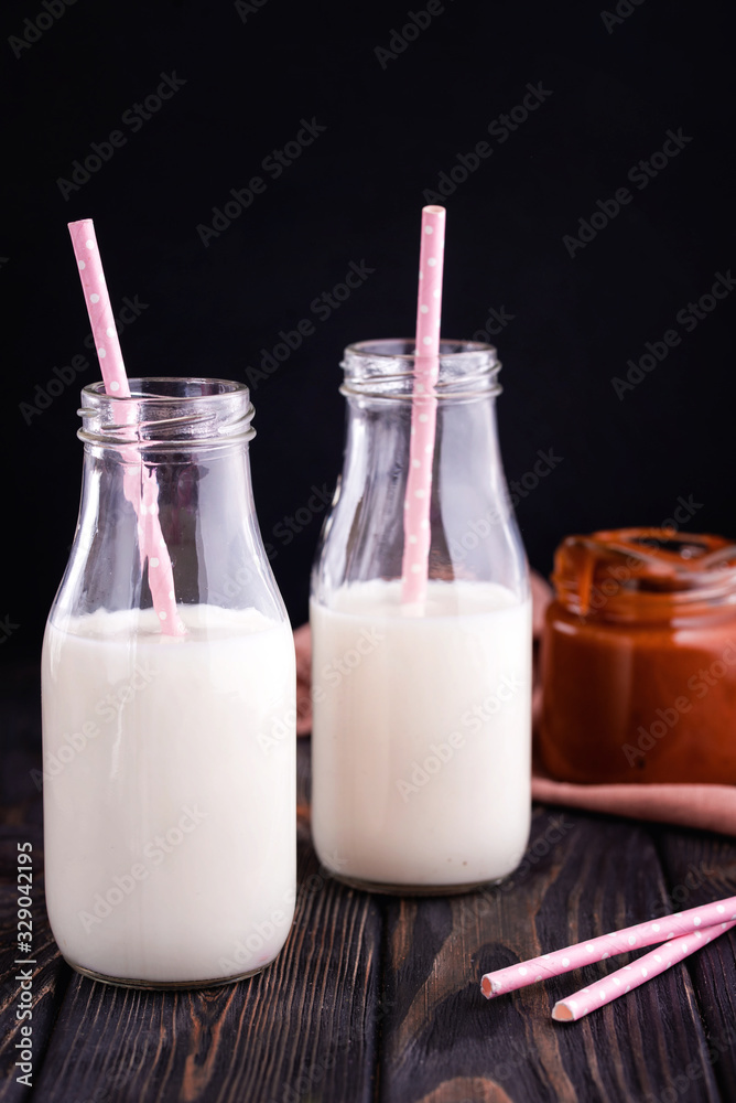 Two glass bottles with fresh milk and tubes on the table.