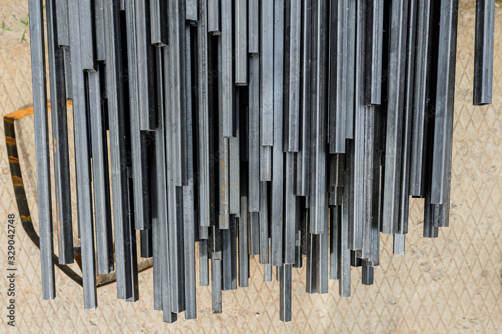 Racks of metal profiles. Metal is stored in an open warehouse. Wet on the street. Background made of iron for shooting flatleys on the table Racks of metal profiles. Metal is stored in an open warehouse. Wet on the street. Background made of iron for shooting flatleys on the table