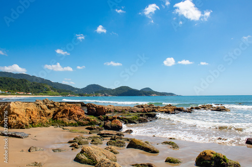 Mar azul esverdeado e pedras de praia tropical< itapema