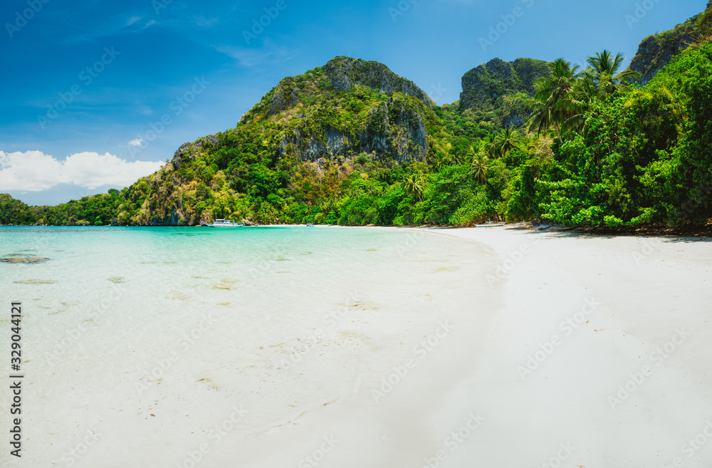 A beautiful tropical sandy beach with limestone hills and lush green jungle trees. Holiday vacation concept