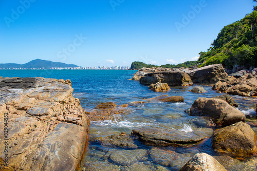 Costa rochosa em praia tropical de Itapema, ao fundo a cidade