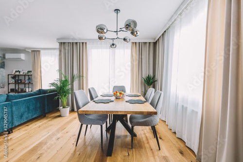Dining room with wooden table and floor in modern apartment.