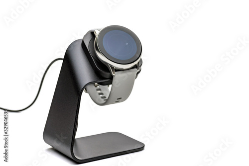 Fototapeta Naklejka Na Ścianę i Meble -  smart watch charging on wireless charging stand pad on white background