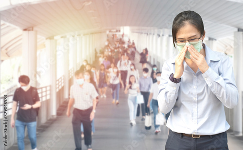 Double Exposure image of Asian worker or business woman wearing surgical mask hands covered her mouth while coughing with blurred of crowed,Wuhan coronavirus (COVID-19) outbreak prevention.