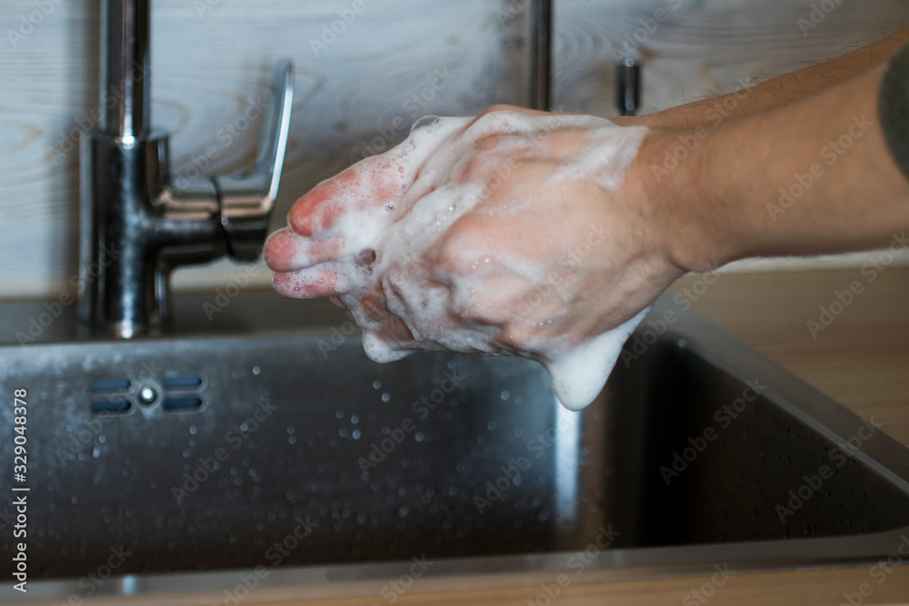 Washing hands in hot water with soap from covid-19 virus at sink man home lifestyle.