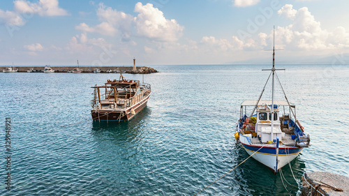 view of small fishing boats parked in a quiet bay of the Greek city of Hersonissos against a blue sky