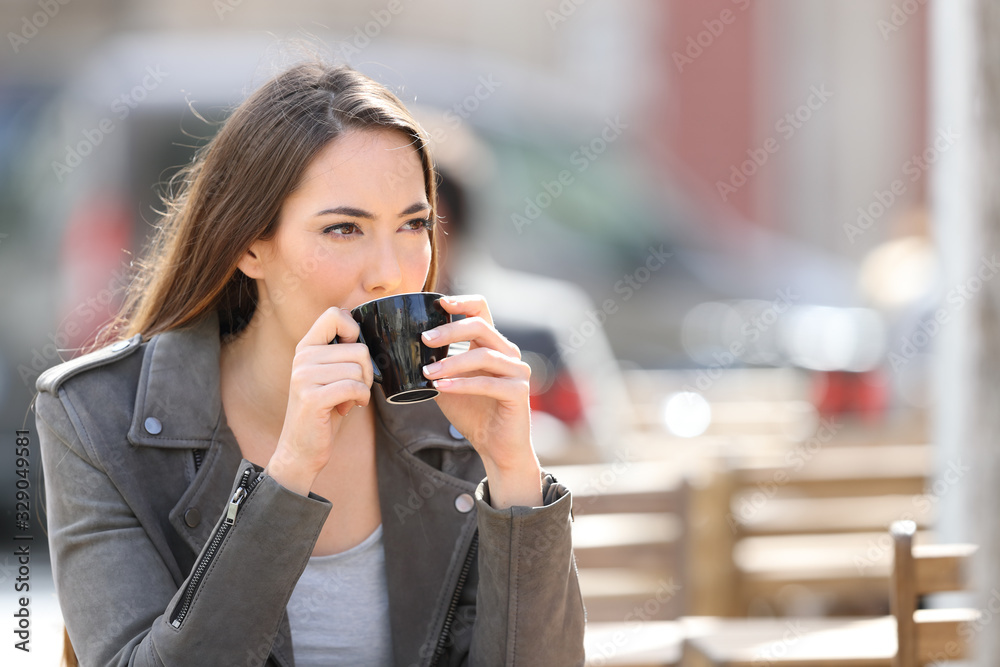 Woman drinking coffee looking away on a terrace