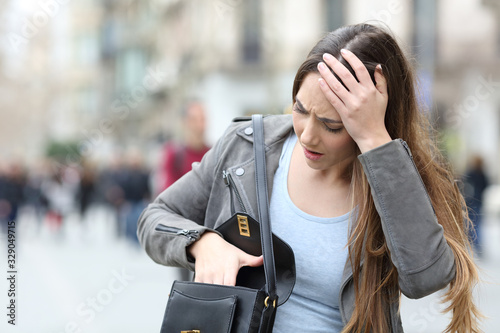 Worried woman looking inside her bag on street