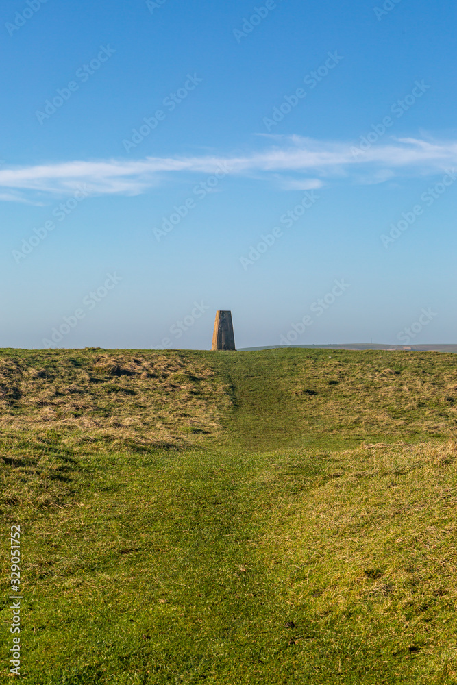 A trig point in the South Downs, with a blue sky overhead