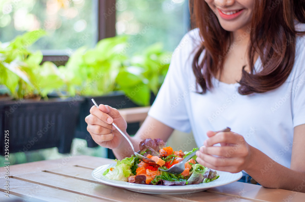 The smiling woman enjoys eating a salmon salad. To lose weight and diet, eat foods that are beneficial to the body. Weight loss concept.