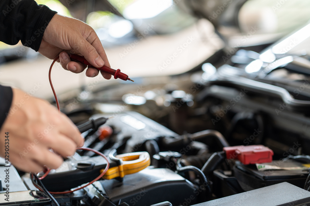 Professional mechanic man holding multimeter tool for testing and troubleshooting failure of a